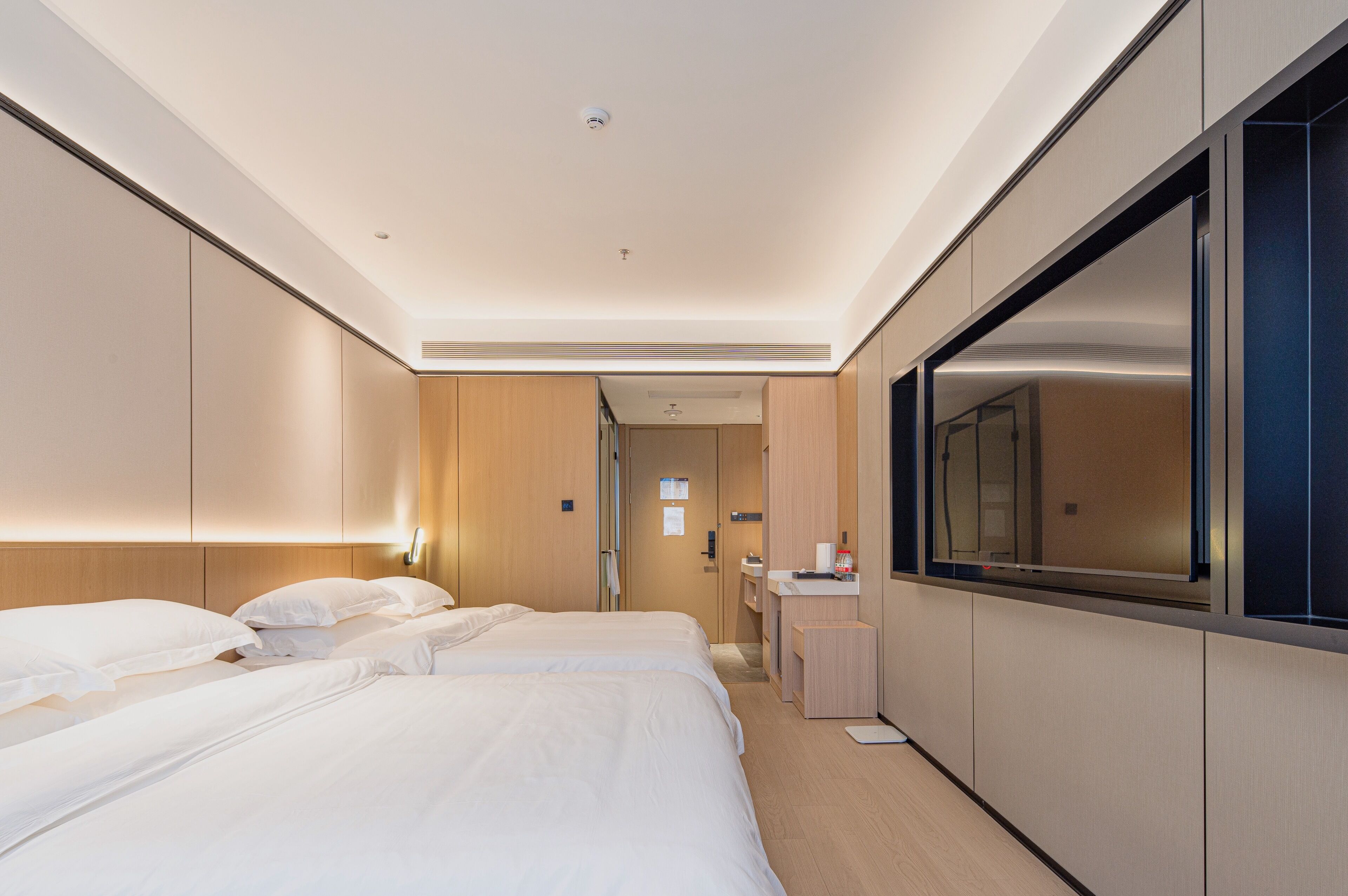 A hotel room with a large bed, a desk, a mirror, and a wardrobe.