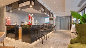 A modern reception area with a counter, bar stools, and a large potted plant. - Dayin Serene Garden Hotel - Shanghai Hongqiao North Xinjing Metro Station (Shanghai)
