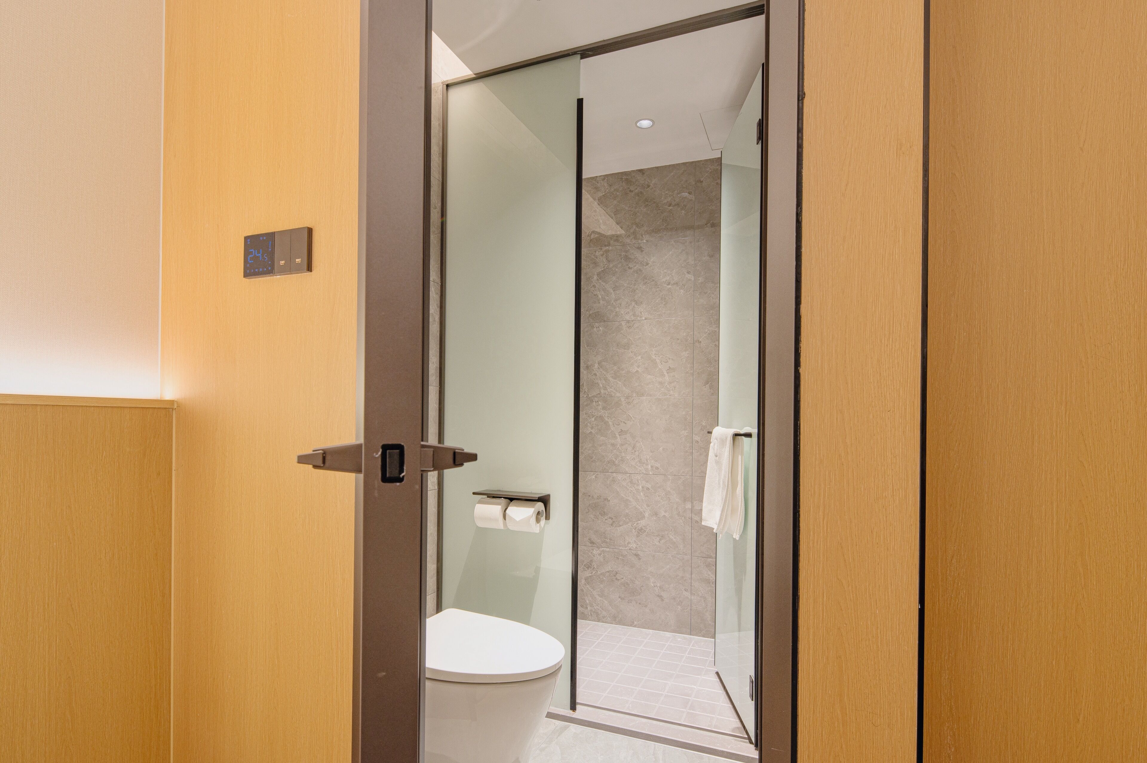 Un baño moderno con cabina de ducha de vidrio, inodoro y perchero para toallas.