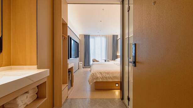 A modern hotel room with a wooden wardrobe, a vanity with a mirror, a bed with a headboard, and a large window with curtains. - Dayin Serene Garden Hotel - Shanghai Hongqiao North Xinjing Metro Station (Shanghai)