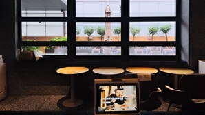 A modern interior with a large window, multiple tables, and a television screen displaying a cartoon. - Dayin Serene Garden Hotel - Shanghai Hongqiao North Xinjing Metro Station (Shanghai)