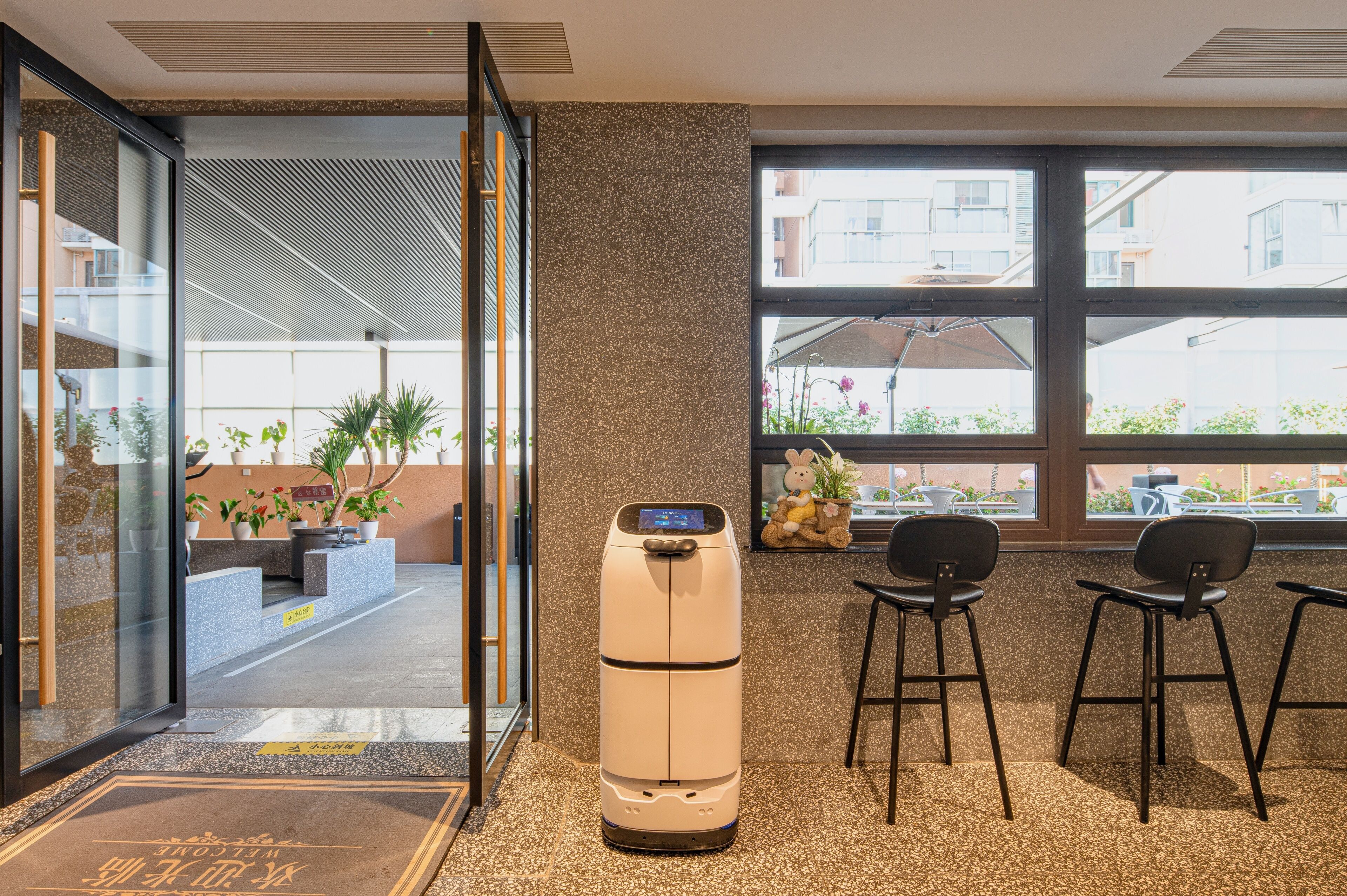 A reception area with a massage chair, a glass door entrance, and a view of the outside balcony.