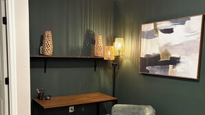 Een kamer met een bureau, stoel, planken en kunstwerken.