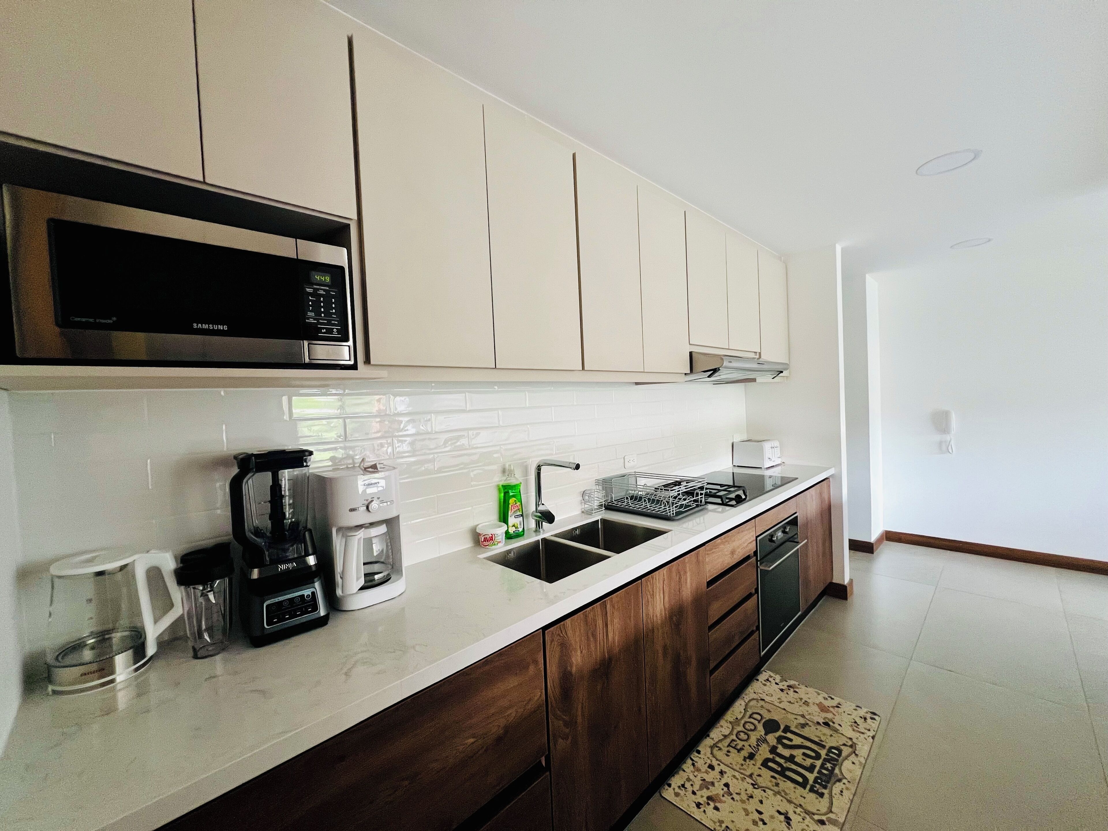 A modern kitchen with white cabinets, a stainless steel microwave, a coffee maker, and a dishwasher.