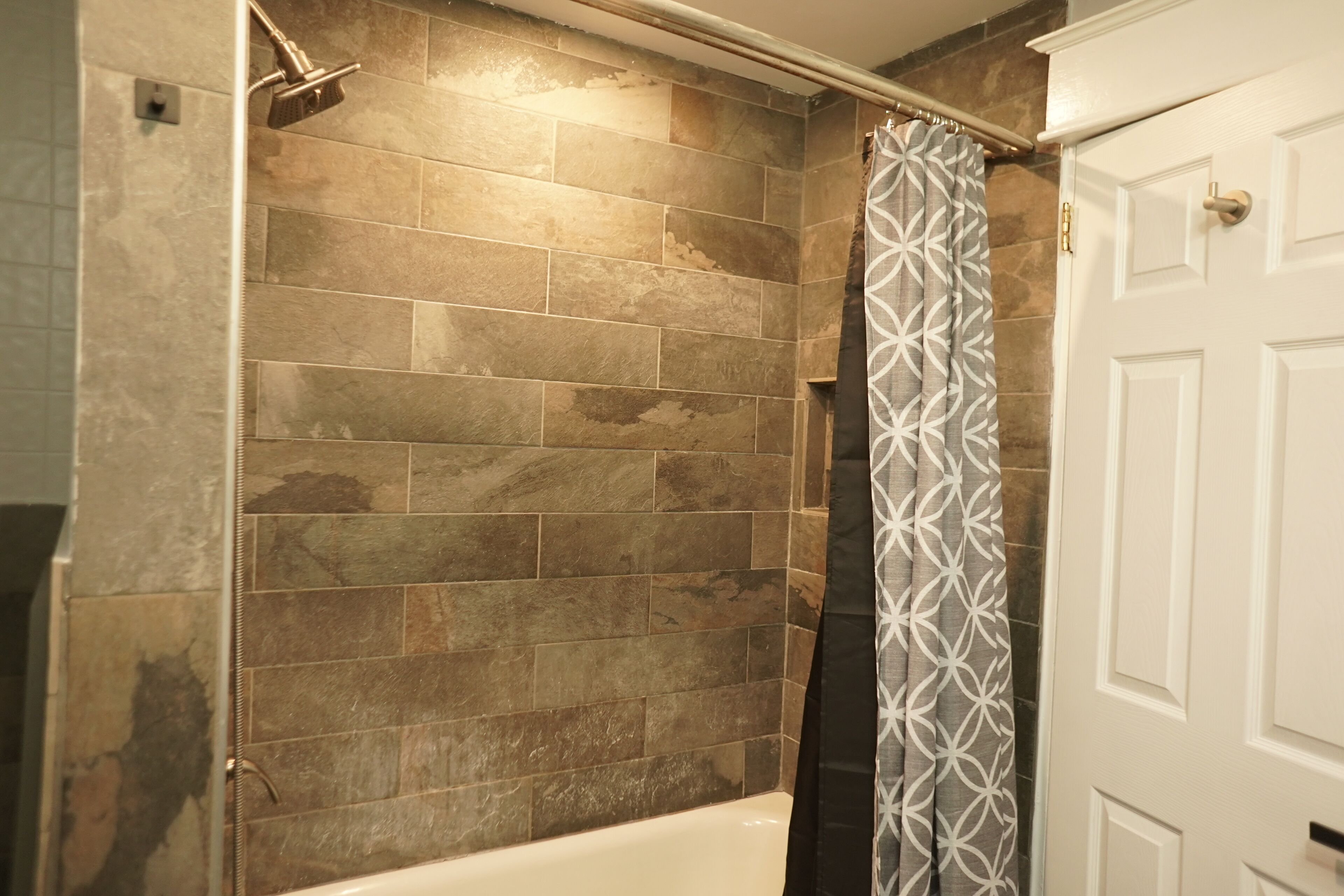 Une salle de bain avec une douche, une baignoire et une porte.