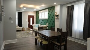 Una sala de estar moderna con una mesa de comedor de madera, un sofá y una pared verde decorativa.