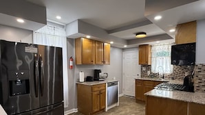 Una cocina moderna con refrigerador de acero inoxidable, gabinetes de madera, encimeras de granito y salpicadero de azulejos.