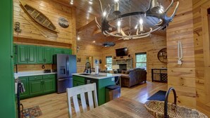 Interior de una cabaña de madera con cocina, comedor y sala de estar.