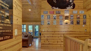 Interior de una cabaña con paredes de madera, un cuero de vaca colgado en la pared y varios letreros informativos.
