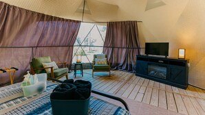 A tented room with a television, seating area, and a fireplace.