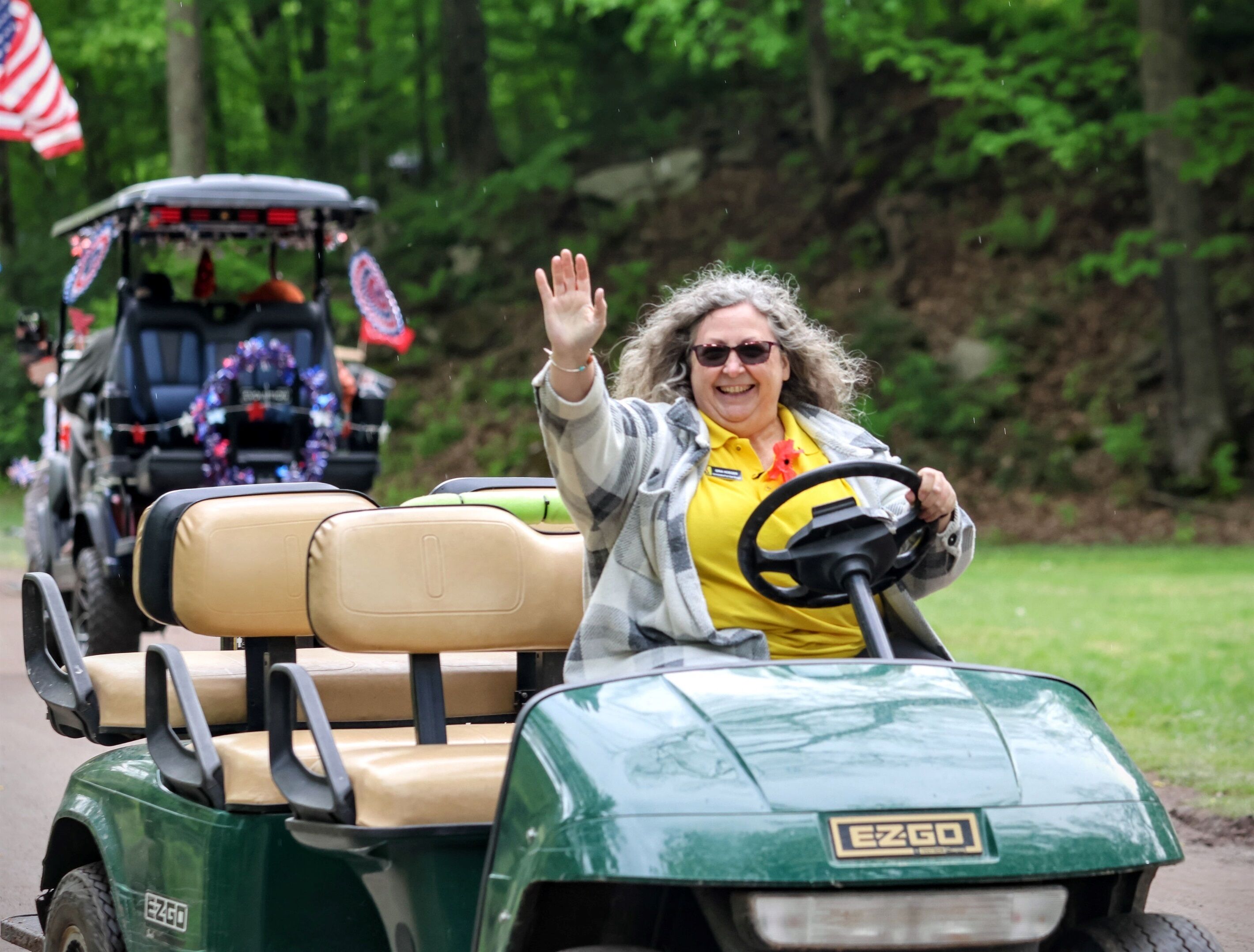 A golf cart with a green body and tan seats, branded with "EZGO".