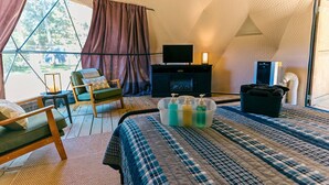 Habitación tipo tienda de campaña con una cama, sillas, un televisor y un espacio de almacenamiento.