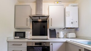 Eine kompakte Küche mit Mikrowelle, Toaster, Wasserkocher, Backofen und Geschirrspüler.