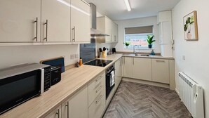 Una cocina moderna con armarios blancos, un microondas negro y un suelo con estampado de espiga.