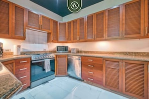 Una cocina con armarios de madera, microondas, horno y lavavajillas.
