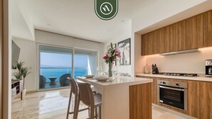 A modern kitchen with a large island, wooden cabinets, and a view of the sea. - Oceanview 1 BR Condo with Pools and Beach Access (Puerto Vallarta)