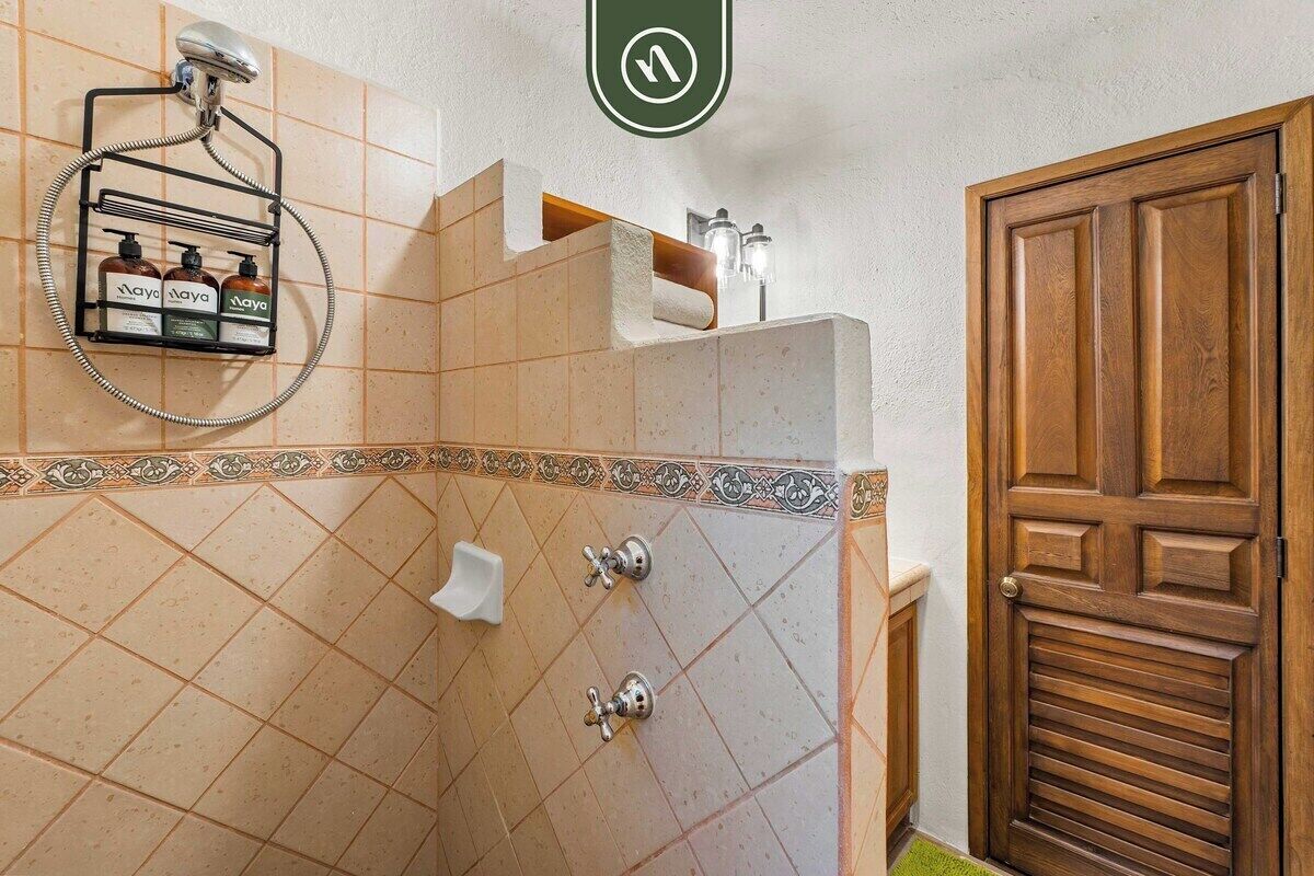 Ein Badezimmer mit Dusche, einer Holztür und einem Handtuchhalter mit Flaschen.