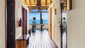 Een gang die uitkomt op een balkon met fitnessapparatuur en een brandblusser aan de muur.