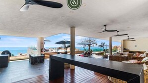 Een ruim buitengebied met een houten terras, lounge fauteuils en uitzicht op de oceaan.