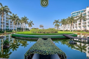 Un hotel con piscina, palmeras y un césped bien cuidado.