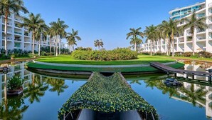 A hotel with a pool, palm trees, and a well-maintained lawn. - Aria Ocean 179 | 1BR, Nuevo Vallarta, pool & beach (Nuevo Vallarta)