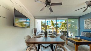 A modern dining area with a large table, chairs, and a ceiling fan. - Aria Ocean 179 | 1BR, Nuevo Vallarta, pool & beach (Nuevo Vallarta)