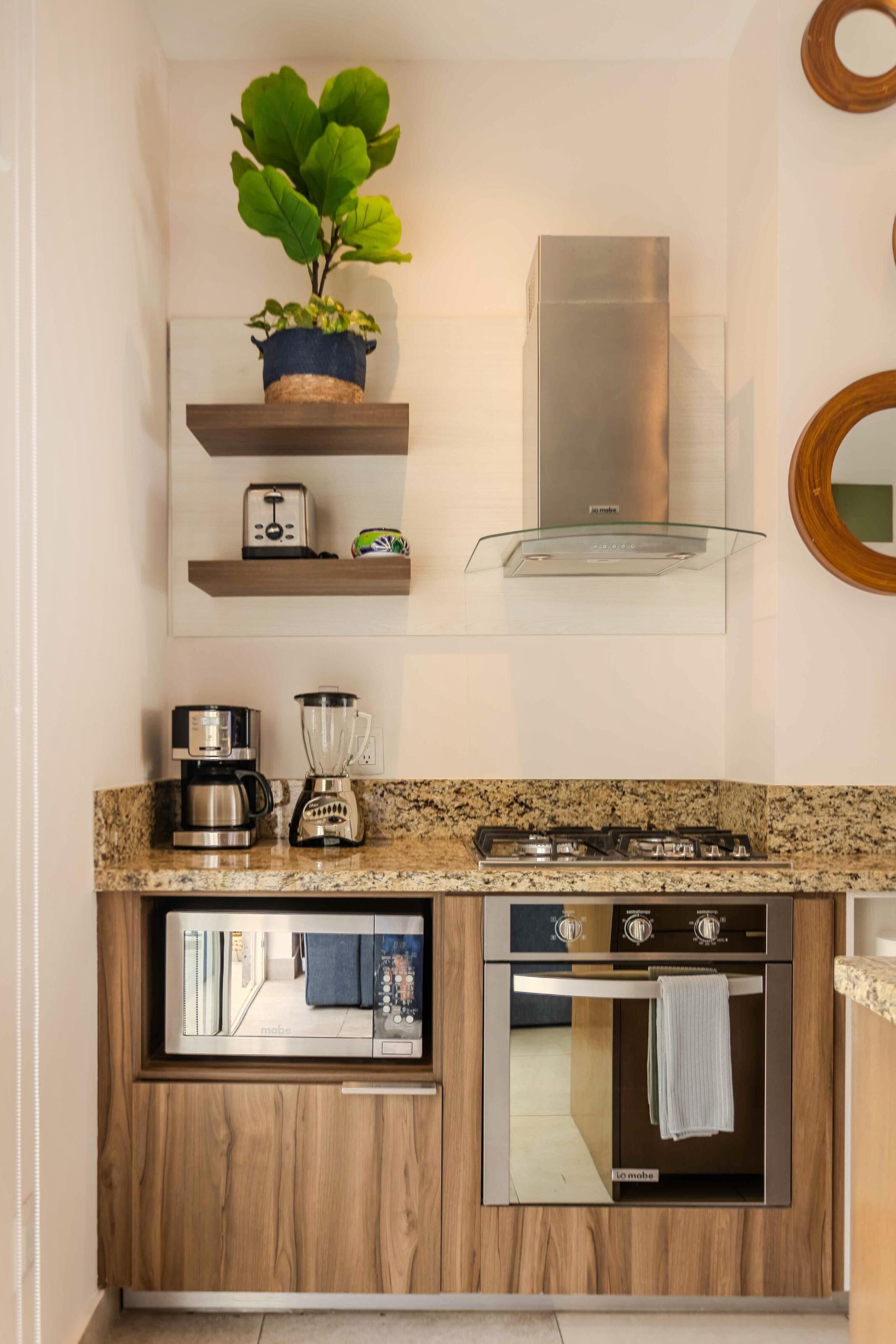 A modern kitchen with a built-in oven, a coffee maker, a blender, and a toaster on the countertop.