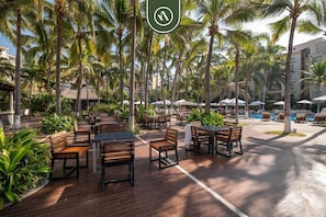 A resort with outdoor seating, palm trees, and a pool area.