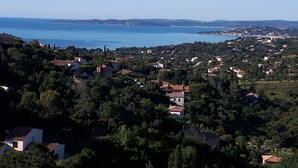 A coastal town with houses surrounded by greenery, a clear blue sea, and distant hills. - Apartment CLIMATISE 4 persons (les  issambres)