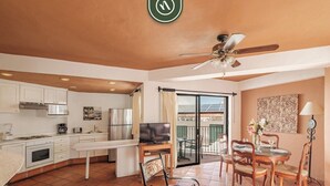 A spacious living area with a kitchen, dining table, and a balcony with outdoor seating.