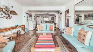Un salon spacieux, comprenant un ensemble de canapés, une table basse et des éléments décoratifs sur les murs.