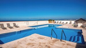 Une piscine avec des chaises longues et vue sur l’océan.