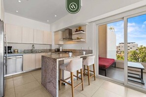 Una cucina moderna con isola centrale, sgabelli da bar e una porta scorrevole in vetro che dà su un balcone.