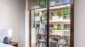 Un balcón con dos sillas, una mesita y una planta en maceta.
