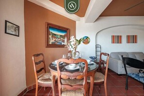 Un coin repas avec une table ronde, des chaises et un vase rempli de fleurs.