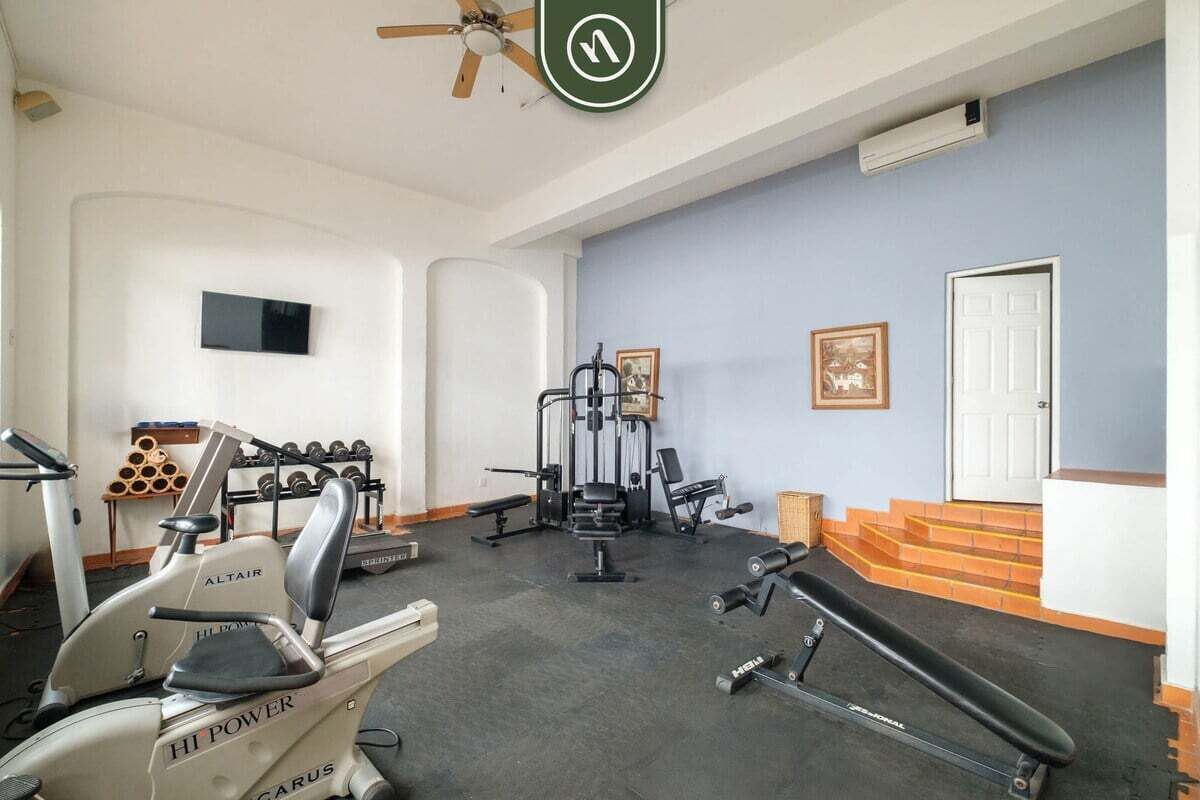 Une salle de sport à domicile équipée de matériel d’exercice, d’un téléviseur et d’un escalier.