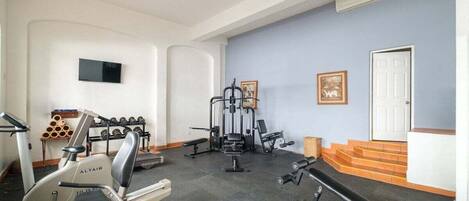 Une salle de sport à domicile équipée de matériel d’exercice, d’un téléviseur et d’un escalier.