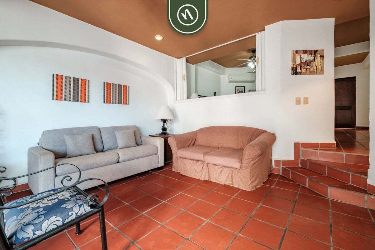 A living room with a sofa, a coffee table, and a staircase leading to another level.