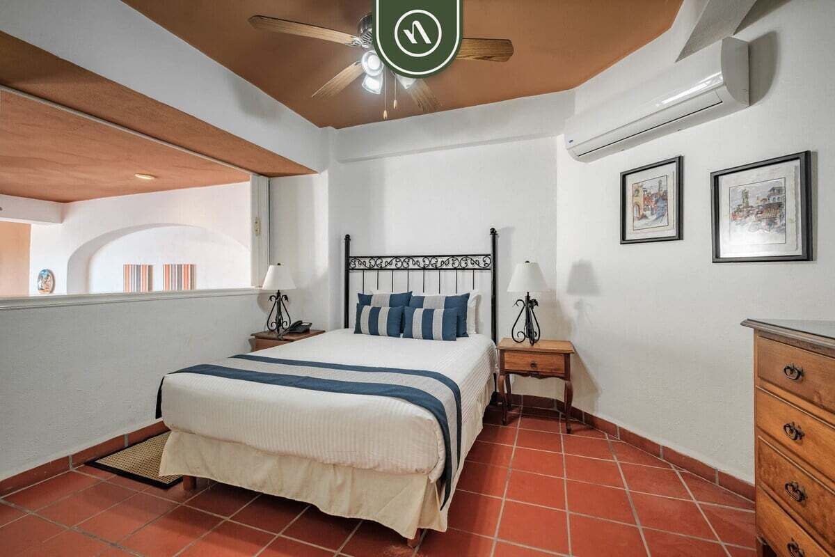 Un dormitorio con cama, mesitas de noche, cómoda y ventilador de techo.