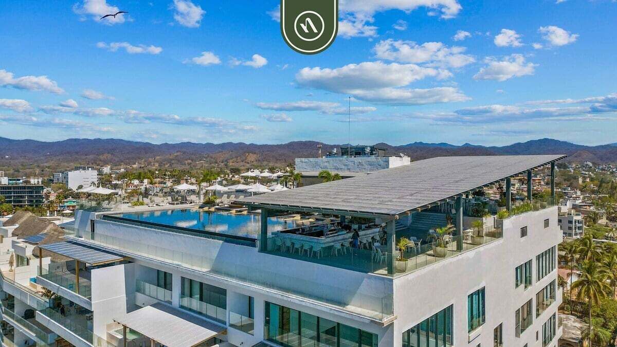 A modern hotel with a rooftop pool and glass balconies.