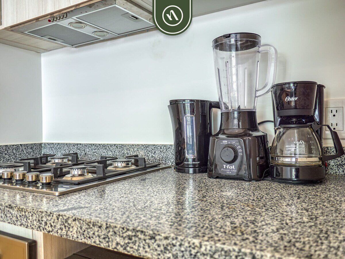 A kitchen with a gas stove, a Hamilton Beach blender, a Tefal rice cooker, and a coffee maker.