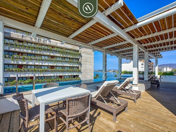 Une terrasse extérieure avec une piscine, des chaises longues et une table.