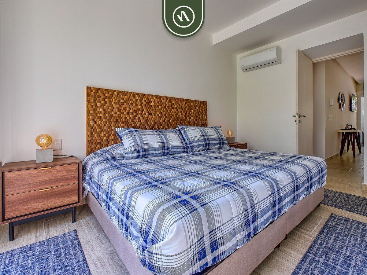 A bedroom with a bed, wooden headboard, bedside tables, and a nightstand.