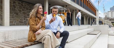 A couple sitting on outdoor steps with a modern building in the background.