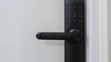 Cerradura electrónica con teclado negro y picaporte, instalada en una puerta blanca.