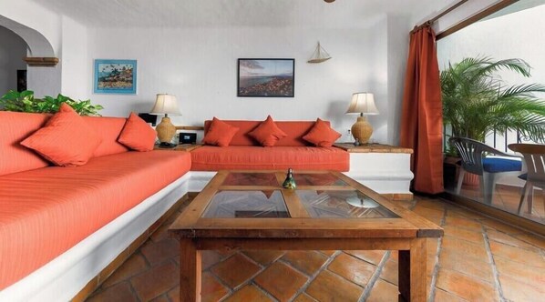 A living room with a sofa set, a coffee table, and a view through a glass door.