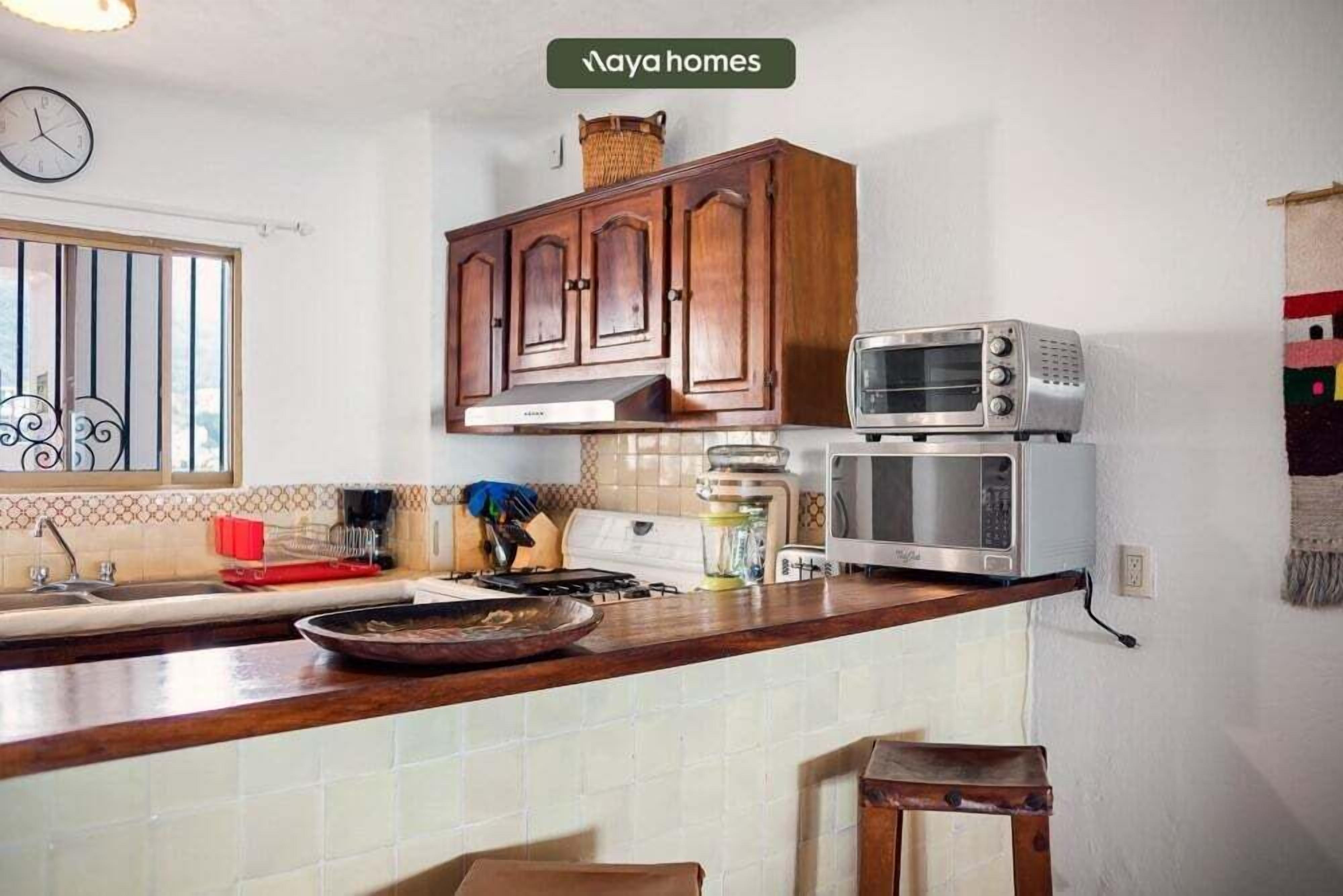 A kitchen with wooden cabinets, a microwave, a stove, and a sink.