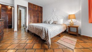 Een slaapkamer met een bed, een houten garderobe en een nachtkastje met een lamp.