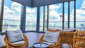A modern room with large windows, wicker furniture, and a city view. - Axon Residence by Emily in Town (Kuala Lumpur)