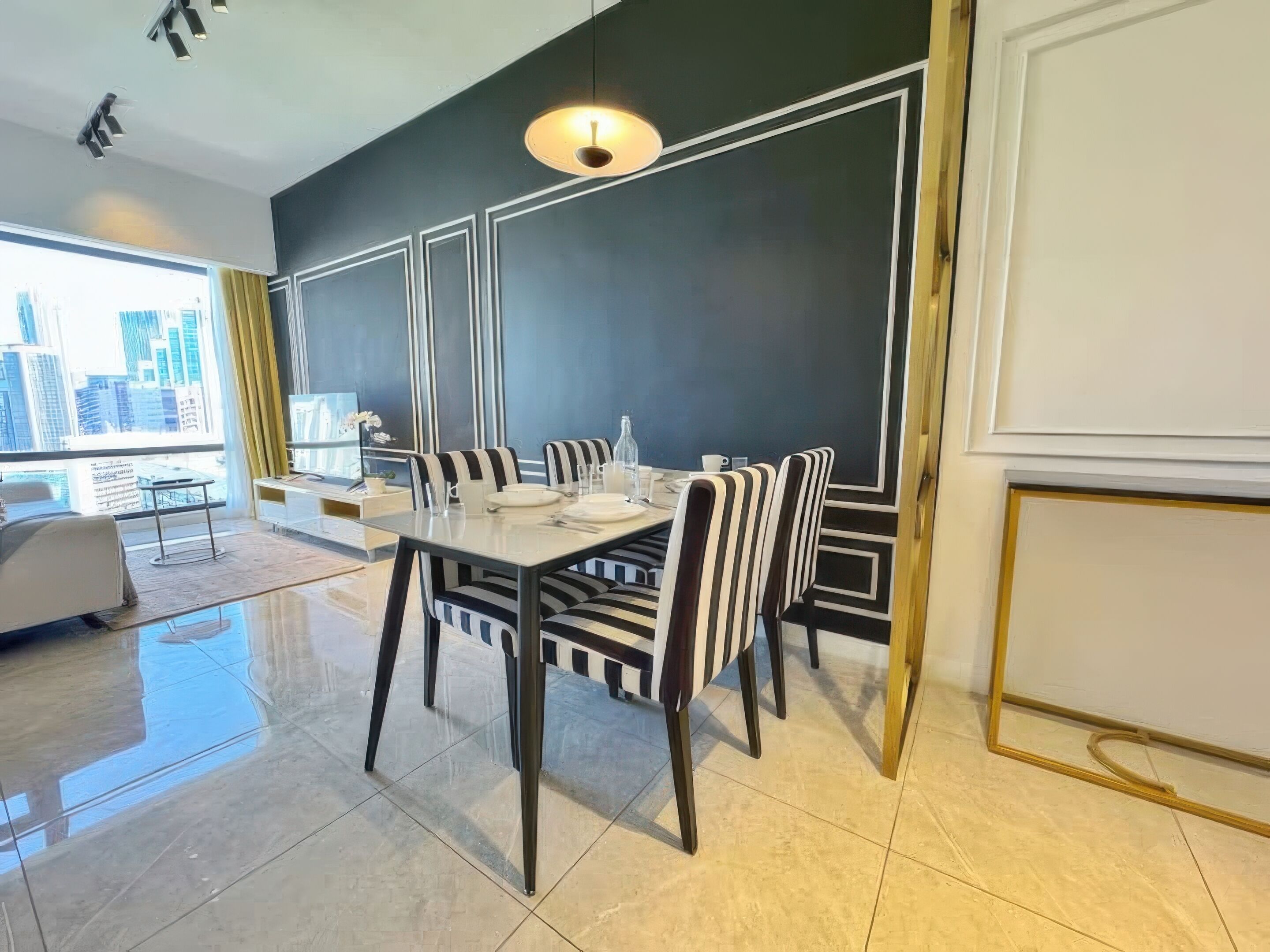 Un espace de restauration moderne avec une table dressée pour quatre personnes, des chaises à rayures et une vue sur la ville grâce à de grandes fenêtres.